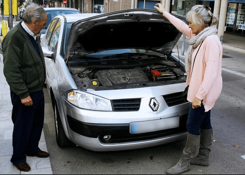 personas mirando el motor del coche
